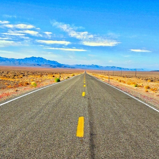 A road stretches out ahead against a blue sky