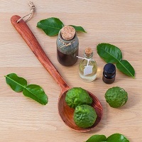 Essential oil bottles with green fruit and leaves