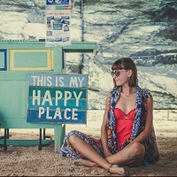 Girl sitting cross-legged next to a sign reading my happy place