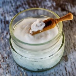 Glass jar of coconut oil with wooden scoop