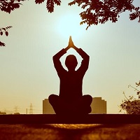 Silhouette of a person in yoga pose silhouetted against a city sky