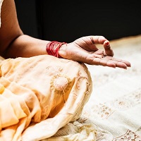 Cross legged yoga pose showing knee and upward facing hand