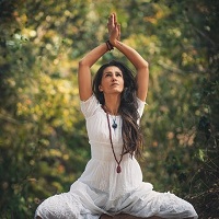 Woman in Kundalini Yoga pose with arms raised above the head