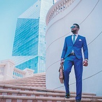 Man wearing a suit, shirt and tie in blue shades, representing the colour of the throat chakra