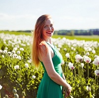 Woman in a green dress surrounded by flowers in a field