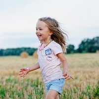 A smiling child runs through a field