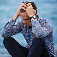 Man appears to have a headache as he holds his head in his hands