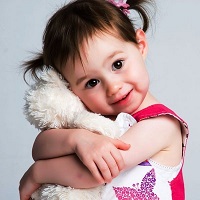 Small child smiling and hugging her teddy