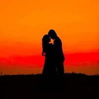 Silhouette of a couple embracing against an orange sky