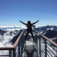 Silhouette of a person with out stretched arms on a platform above the clouds