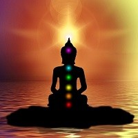 Silhouette of person meditating with chakra points lit in their representative colours