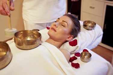 Woman surrounded by singing bowls for sound therapy session