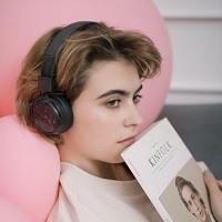 Profile of girl with headphones on and book in her hand