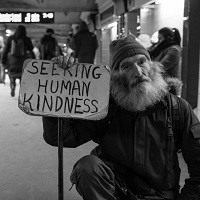 Homeless man holding a sign saying seeking human kindness