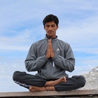 Man sits cross legged with hands together in a yoga pose