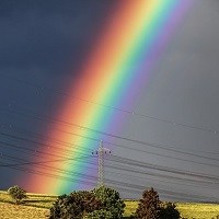 A rainbow stretches across a dark grey sky