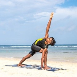 Man holding yoga pose on the beach