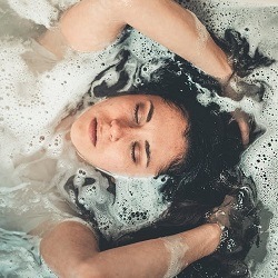 Head and arms of a woman in the bath cleansing her aura