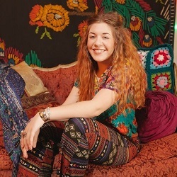 Smiling girl sits on settee against a colourful background