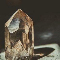 A crystal wand casts a shadow against a black background