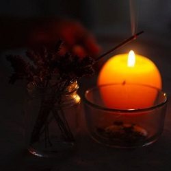 A candle and incense stick burn gently in a sacred space